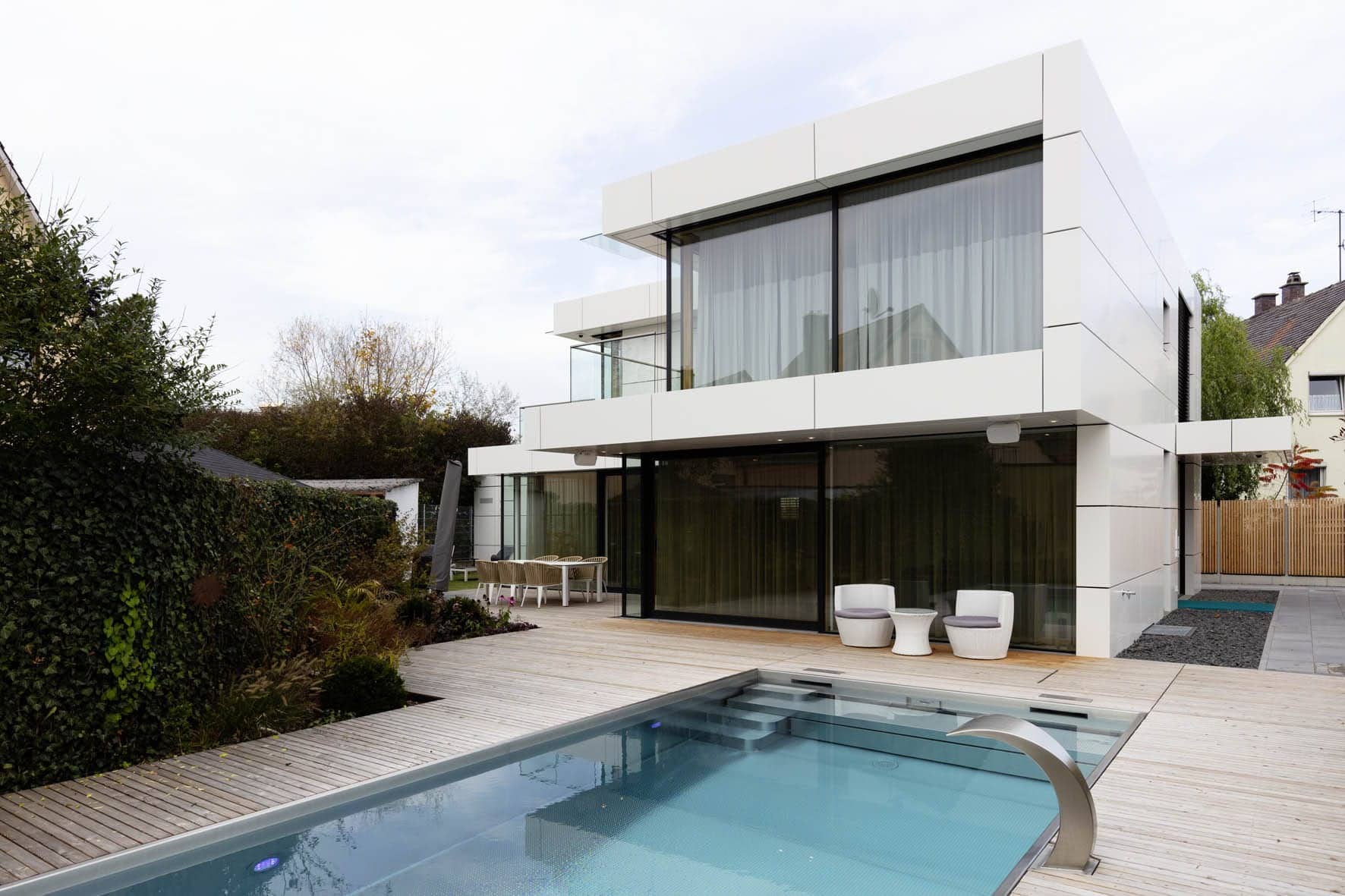 Haus mit vielen Fenstern, weißer Fassade und einem Pool im Garten