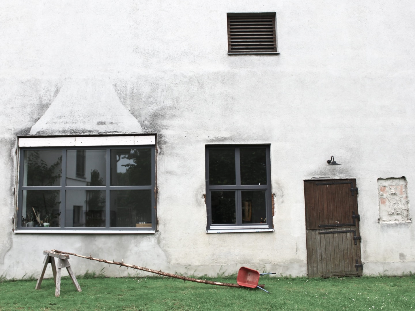 weißes Haus mit einer alten Holztür und zwei neuen Fenstern mit grauem Rahmen