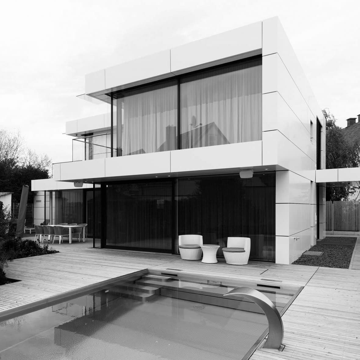 Haus mit vielen Fenstern, weißer Fassade und einem Pool im Garten