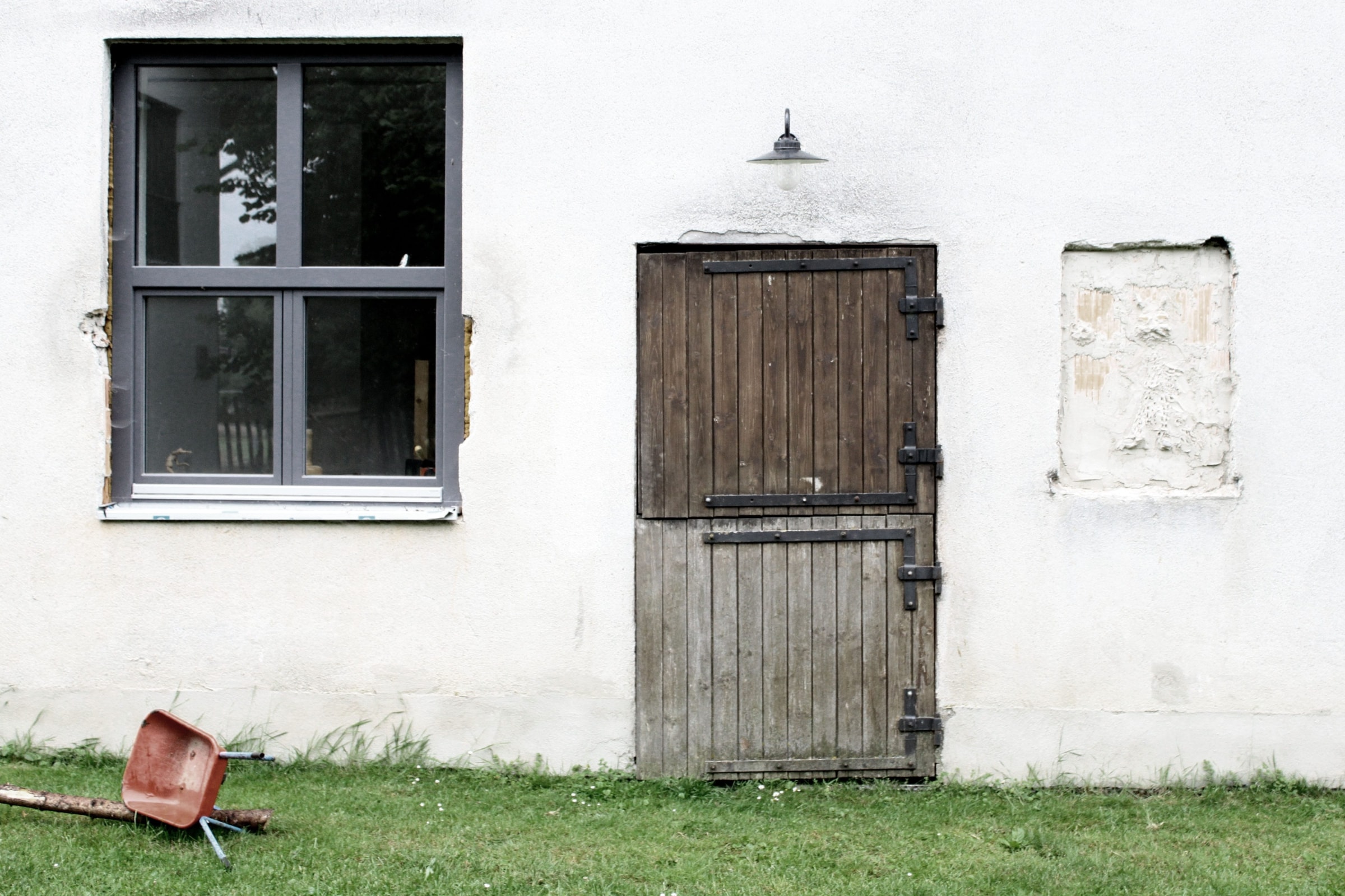 weißes Gebäude mit Holztür und Fenster mit grauem Rahmen