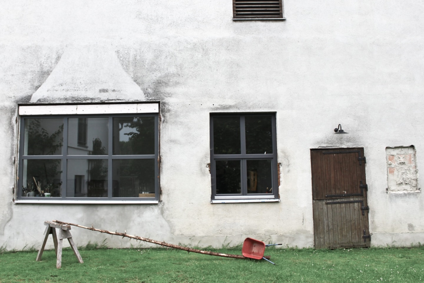 weißes Gebäude mit Holztür und Fenster mit grauem Rahmen