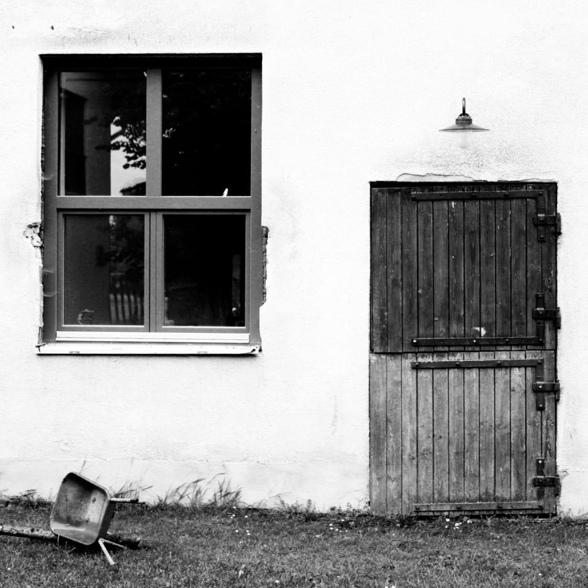 weißes Gebäude mit Holztür und Fenster mit grauem Rahmen