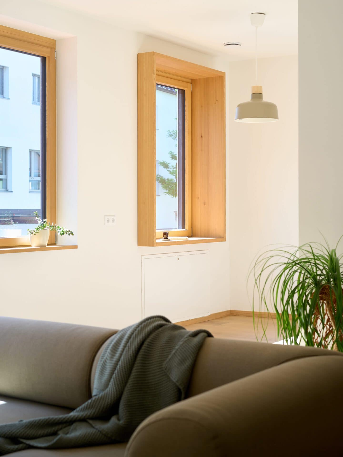 Wohnbereich mit Couch und zwei Fenstern mit Holzumrandung