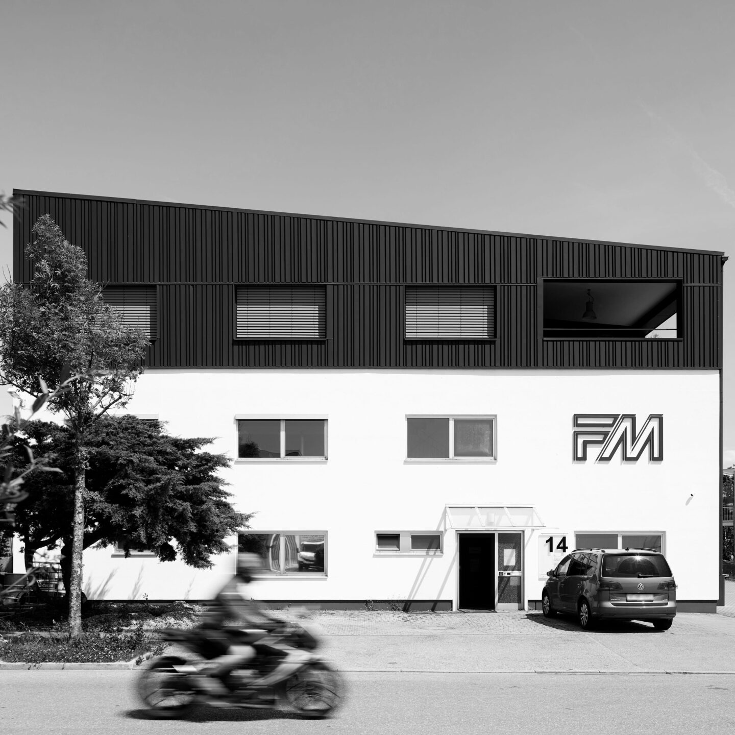 schwarz weiß Bild eines Firmengebäudes mit grauer Aufstockung