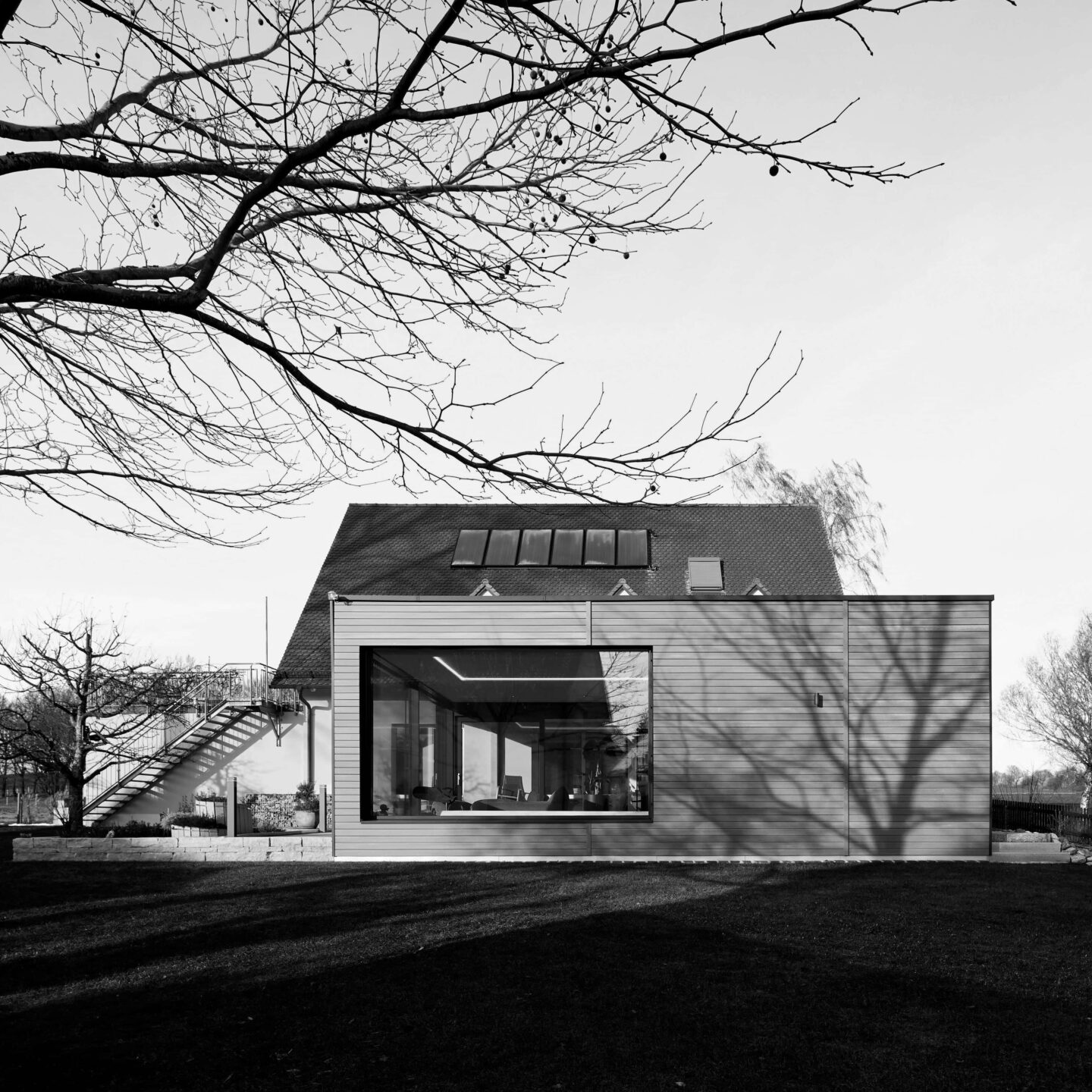 schwarz weiß Bild eines Einfamilienhauses mit angebautem Poolhaus