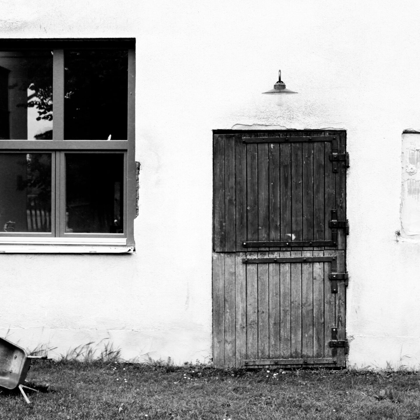 schwarz weiß Bild einer alten Stalltür und einem neuen Fenster