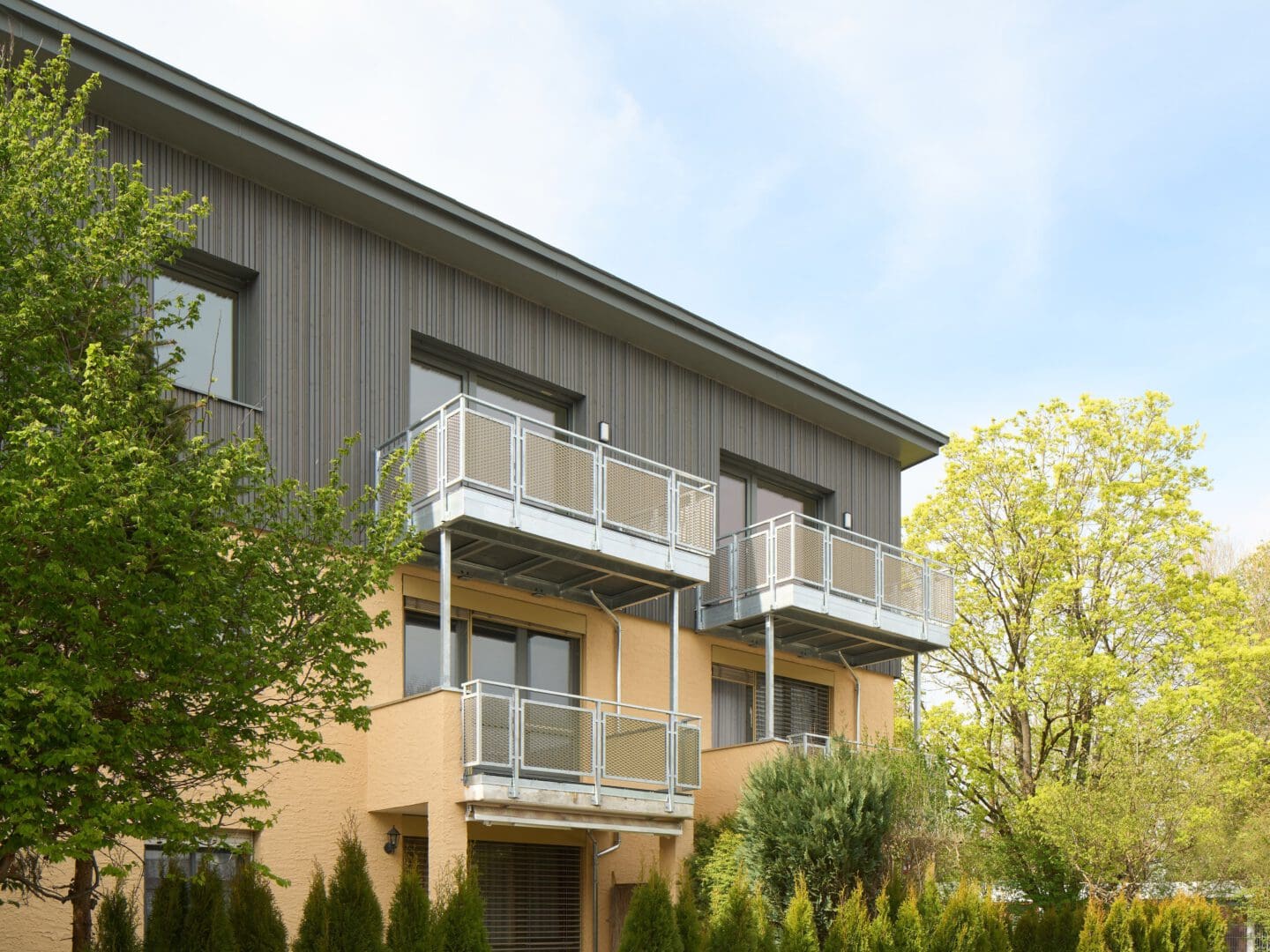 gelbes Mehrparteienhaus mit grünen Bäumen und blauem Himmel