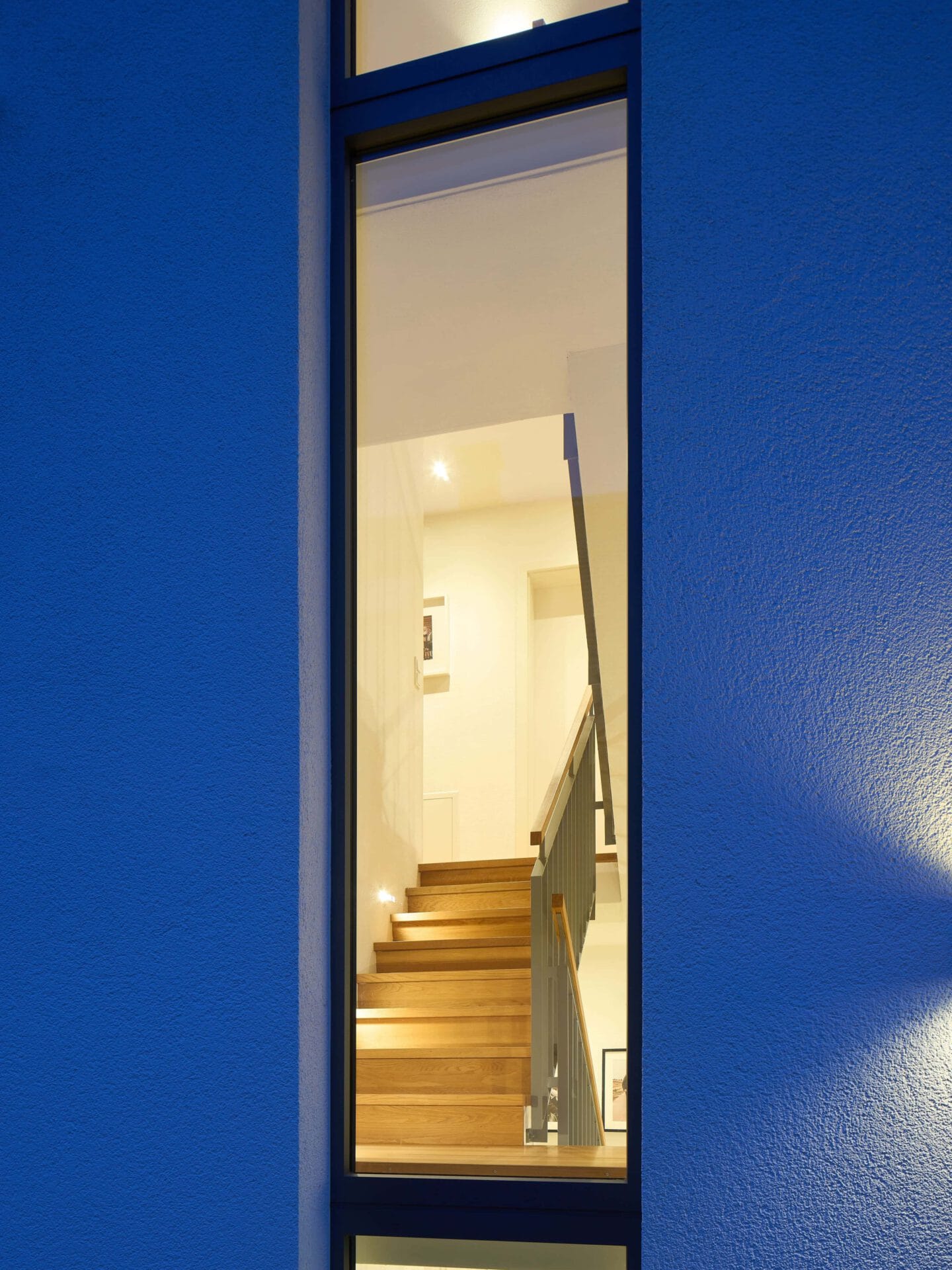 Blick durchs Fenster ins Treppenhaus eines Doppelhauses auf eine Holztreppe
