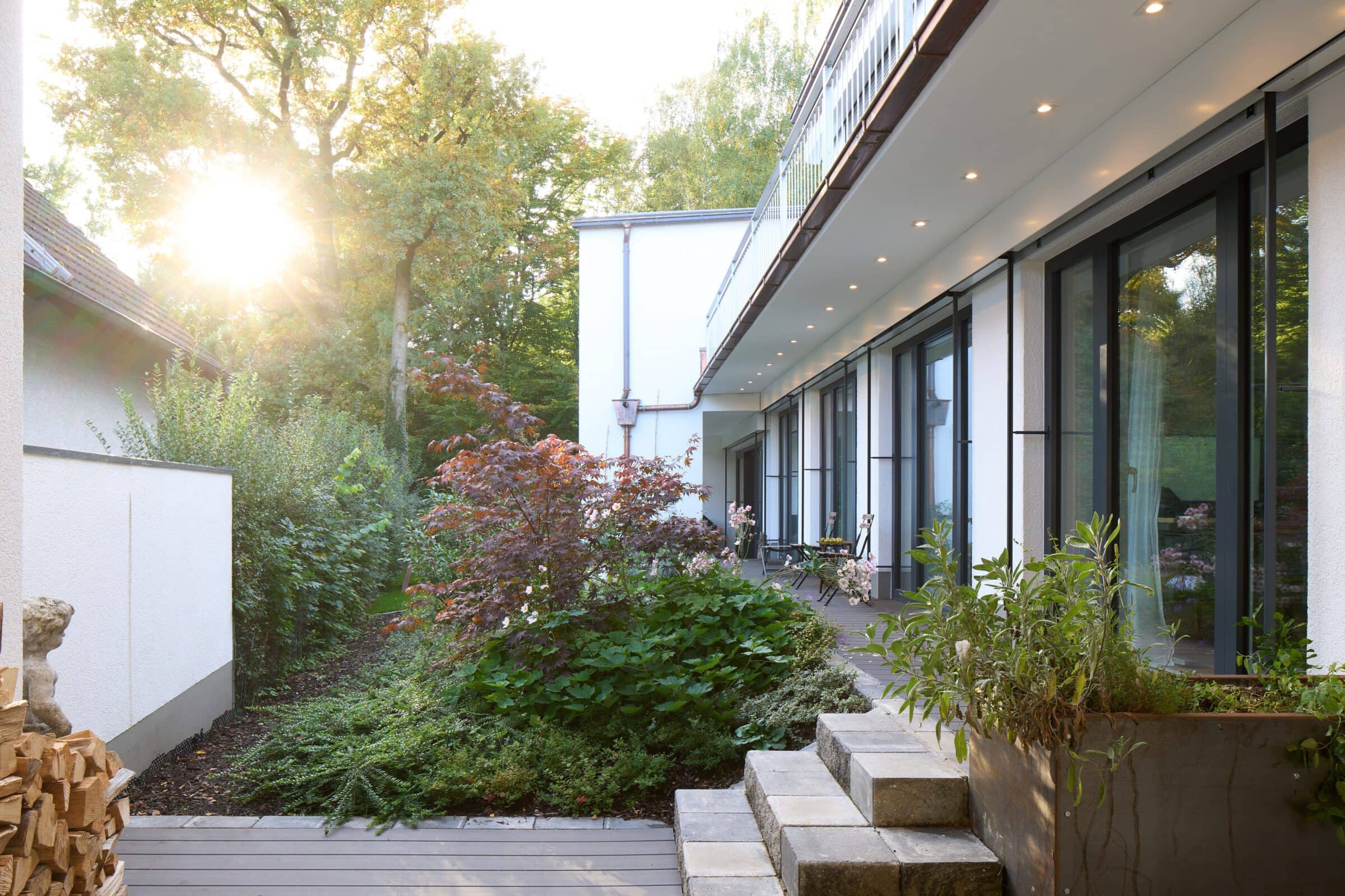 Blick in einen dicht bewachsenen Garten eines umgebauten Einfamilienhauses