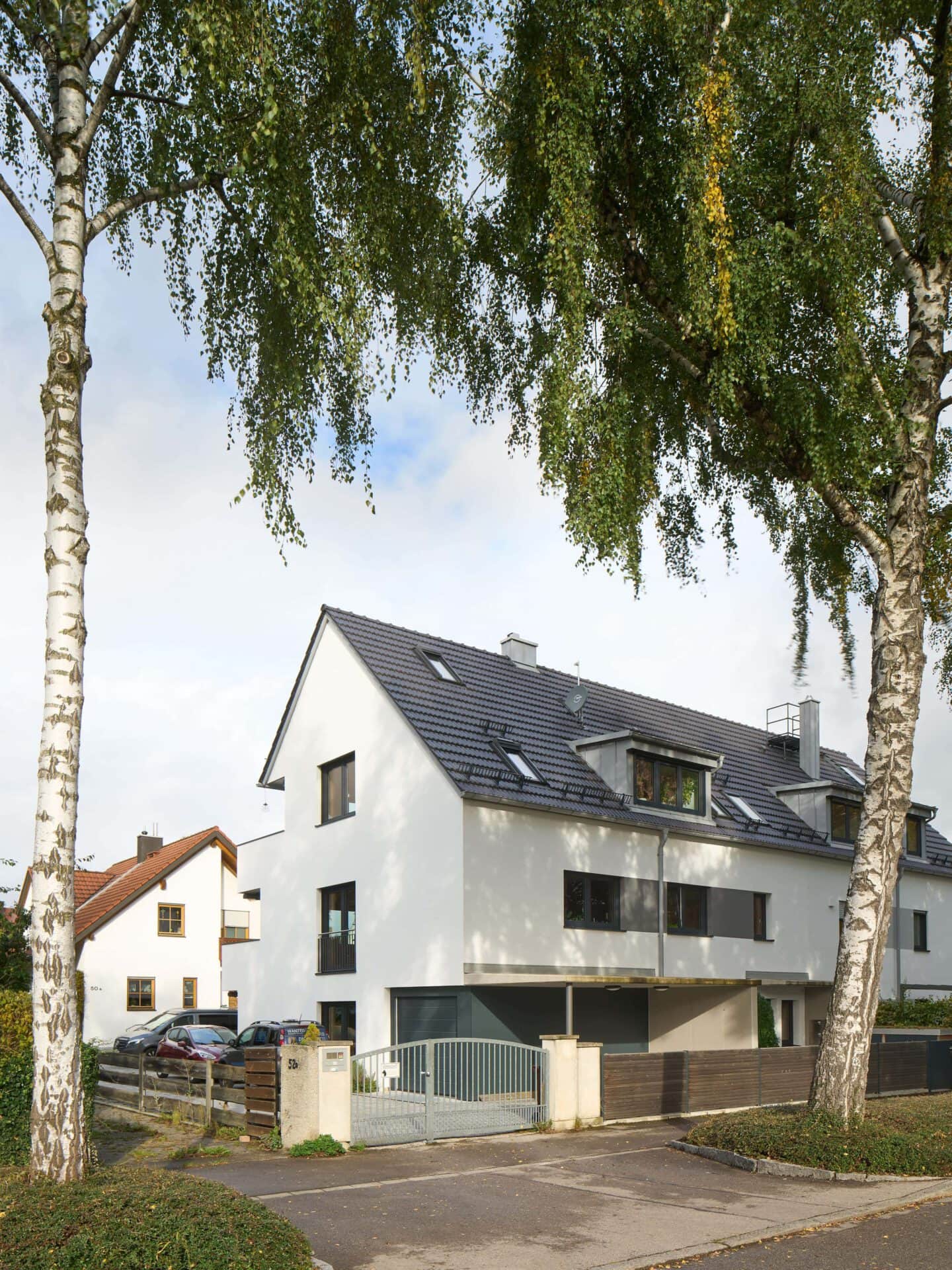 Aufnahme eines neu gebauten Doppelhauses für drei Wohneinheiten mit Birkenbäumen im Vordergrund